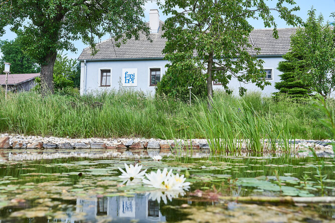 Seitenansicht des Bio-Bauernhof Frei-Hof mit Regenwasser-Speicherteich | © SONNENTOR/@nudlholz.at