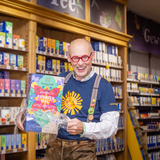 Am Foto ist Hannes mit einer riesigen Packung Happiness Is Probier Mal Tee, von dem er die Plastikfolie zieht.  | © SONNENTOR