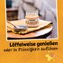 Illustration mit SONNENTOR MÁNUKA Bio-Blütenhonig aus Neuseeland im Glas mit silbernem Deckel und dem Schriftzug: "Löffelweise genießen oder in Flüssigkeit auflösen" auf orangem Hintergrund.