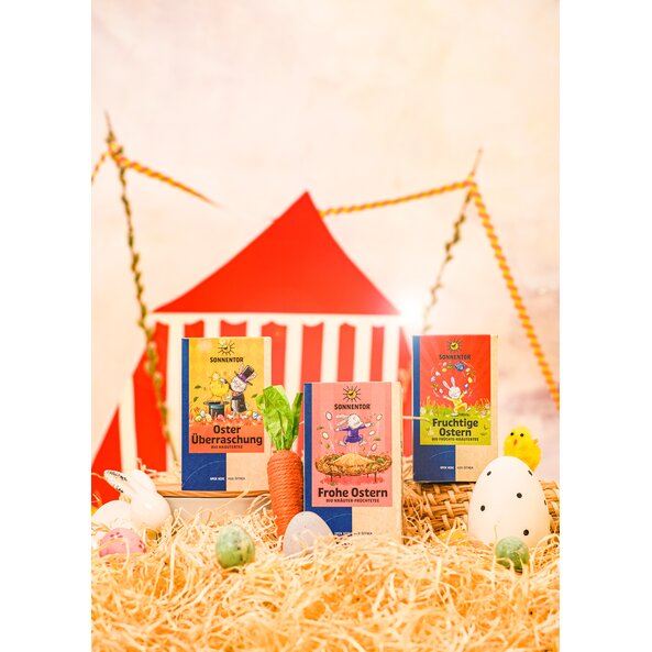 Photo showing three Easter tea packs decorated with Easter eggs and bunnies, with a circus tent in the background.