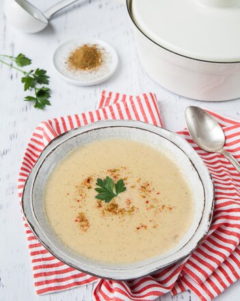 Auf dem Foto ist ein Teller mit Kartoffel Gemüse-Suppe zu sehen. Das Teller steht auf einem rot-weiß kariertem Tuch. | © SONNENTOR