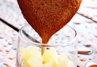 Auf dem Foto sieht man ein Vollkorndinkelherz auf einem Holzstäbchen in einem Glas mit Apfel-Zimt Kompott. | © SONNENTOR