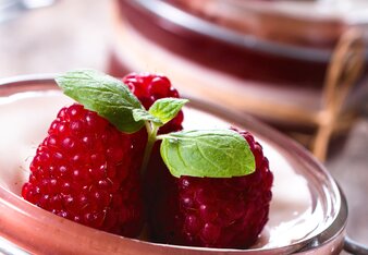 Auf dem Foto ist ein Glas mit Kokos-Pannacotta zu sehen. Oben darauf sind Himbeeren zu sehen. | © SONNENTOR