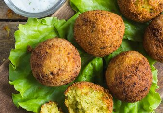 Auf dem Foto sind Falafel auf einem grünen Blatt Salat zu sehen. Daneben sieht man eine kleine Schüssel mit Gurkenraijta. | © SONNENTOR