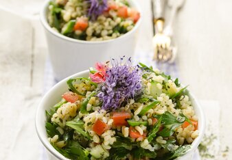 Auf dem Foto sind zwei Schälchen mit buntem Bulgursalat mit lila Blüten zu sehen. | © SONNENTOR