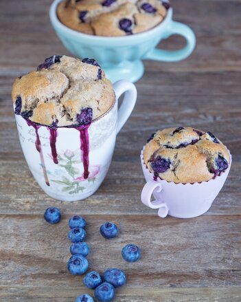 Auf dem Foto sind drei Tassen mit Heidelbeer-Anis-Tassenkuchen zu sehen. Davor sieht man auch frische Heidelbeeren. | © SONNENTOR