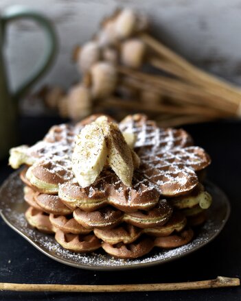 Auf dem Foto sind vier übereinander liegende Waffeln zu sehen. Garniert mit Bananenscheiben und Gewürzen. | © SONNENTOR