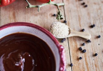 Foto von einem Schälchen mit BBQ Sauce mit Whiskey und Heidelbeeren. Auf dem Foto sind auch Paprika und eine Tomate zu sehen. | © SONNENTOR