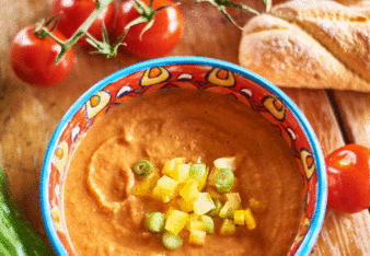 Auf dem Foto ist eine Schale mit klassischer Gazpacho zu sehen. Rundherum liegen Brot, Paprika, Tomaten und eine Gurke. | © SONNENTOR