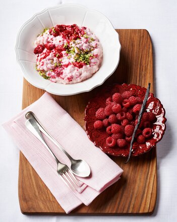 Auf dem Foto ist das rosa Beerendufteis in einer weißen Schale zu sehen. Daneben steht ein Teller mit frischen Himbeeren. | © SONNENTOR