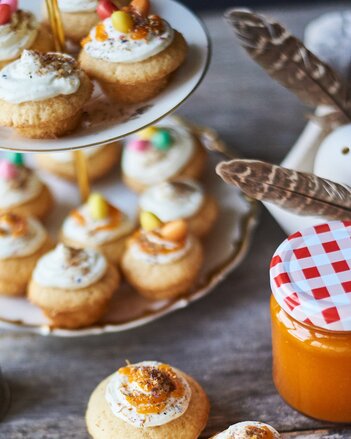 Auf dem Foto ist eine Etagere zu sehen mit vielen Cupcakes darauf. Daneben steht ein Marmeladen Glas und auch Federn sind zu sehen. | © SONNENTOR