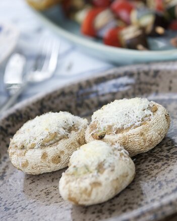 Auf dem Foto sind drei Stück gefüllte Pilze zu sehen. Sie sind mit Parmesan bestreut. | © SONNENTOR