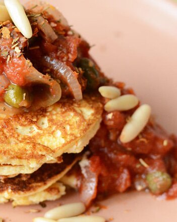 Auf dem Foto sieht man würzige Pancakes mit Tomaten-Kapern-Ragout darüber. | © SONNENTOR