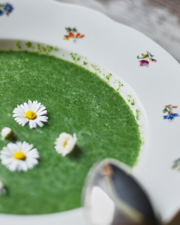 Auf dem Foto sieht man einen Suppenteller mit Wilde Kräutersuppe. Darin sind Gänseblümchen zu sehen. | © SONNENTOR