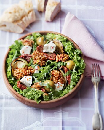 Auf dem Foto ist eine Schüssel gefüllt mit Salat und Risotto zu sehen. Im Hintergrund liegen aufgeschnittene Baguette. | © SONNENTOR