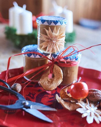 Auf dem Foto sind drei Gläser mit Lebkuchenmarmelade zu sehen. Sie sind mit getrockneten Apfelringen, Holzsternen und Bändern dekoriert. | © SONNENTOR