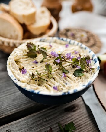 Die Kräuterbutter ist in einem Schüsserl, dekoriert mit essbaren Blüten.  | © SONNENTOR