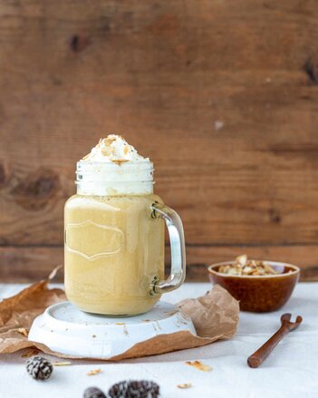 Auf dem Foto ist ein Glas mit Kürbis Latte zu sehen. Darauf ist eine Obershaube mit Mandelblättchen. | © SONNENTOR