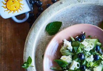 Auf dem Foto ist ein Teller voll mit Salat zu sehen. Dahinter liegen Heidelbeeren. | © SONNENTOR