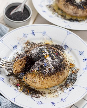 Auf dem Foto sieht man einen Teller mit einer veganen Germknödel. Darauf sieht man die bunten Gewürzblüten. | © SONNENTOR