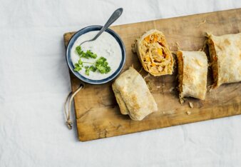 Auf dem Foto ist ein Brett mit Sauerkraut-Kimchi-Strudel zu sehen. Daneben steht eine Schale mit Dip. | © SONNENTOR