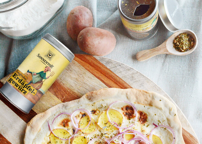 Auf dem Foto sieht man Focaccia mit Kartoffeln und roten Zwiebeln. Daneben sieht man eine Dose Sieglindes Erdäpfelgewürz. | © SONNENTOR